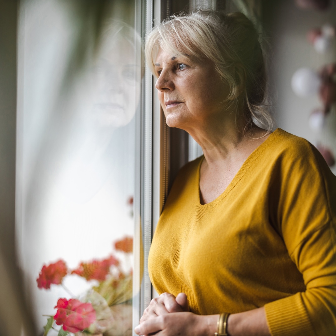 rouwende vrouw kijkt uit raam en denkt na over hoe ze kan omgaan met verlies