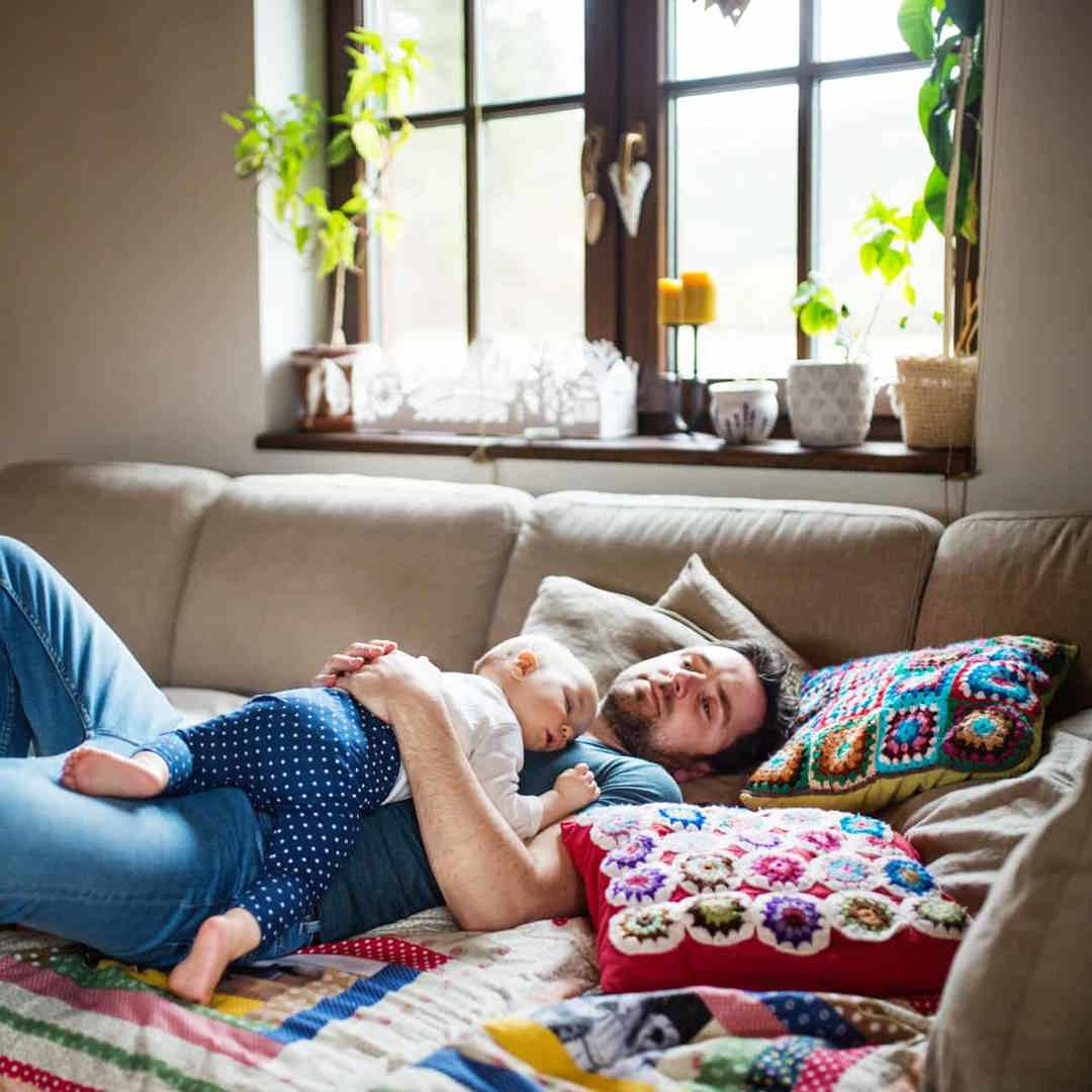 Vermoeide papa slaapt met baby in zetel